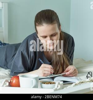 Social media, digital detox. Quarantine, self-isolation, sociophobia. Beautiful girl write dairy Stock Photo