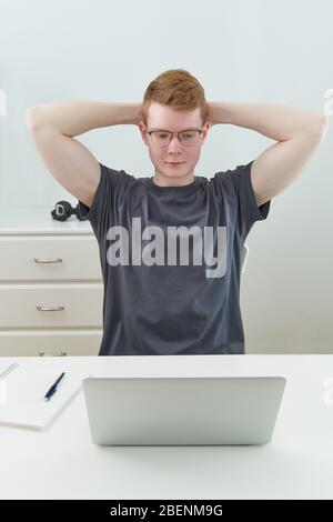Distance learning or working. Quarantine, self-isolation, man is sitting with his hands behind his head, tired Stock Photo