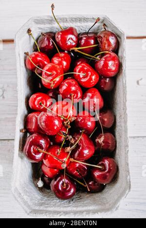 Fresh organic cherries in paper box over dark stone rustic background. Top view. Fresh ripe cherries. sweet cherry Stock Photo