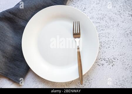 Empty white plate next to a gray kitchen towel Stock Photo