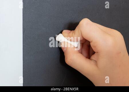 Child's hand writes in chalk on a black chalkboard. Stock Photo