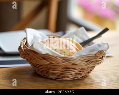 French bread sliced in a basket on a wooden table near the window. Stock Photo