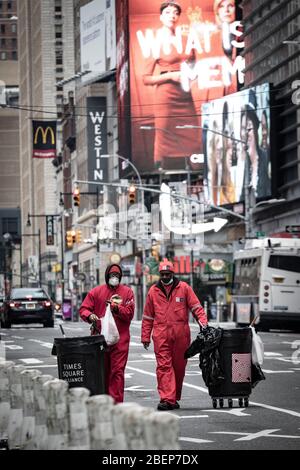 Sanitation workers in Times Square area streets, cleaning litter in city on foot with rolling trash cans and in red uniforms. Stock Photo