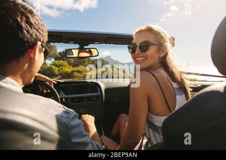 Beautiful woman going on a roadtrip with her boyfriend. Couple going on a long drive in a convertible car. Stock Photo
