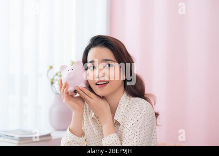 Closeup portrait happy, smiling business woman, holding pink piggy bank Stock Photo