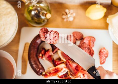 Homemade dry cured smoked spicy sausage.Delicatessen meats. Charcuterie board assembly.Meat/protein snack.Pepperoni pizza topping.Thin slices of sausa Stock Photo