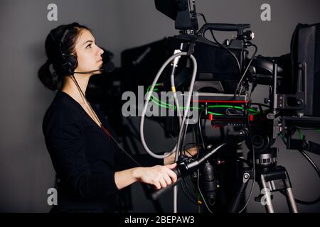 Recording show at TV studio.Professional camera operator with camera in television news broadcast.Camerawoman working with big positioned broadcasting Stock Photo