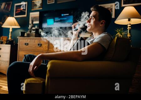 Parent use of e cigarettes in the home.Young man inhaling of a