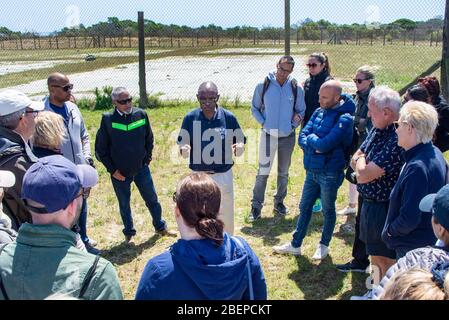 A tour guide gives a talk about life in the prison to tourists. He is a former political prisoner on Robben Island. He is passionate about his politics and tells a good story. Stock Photo