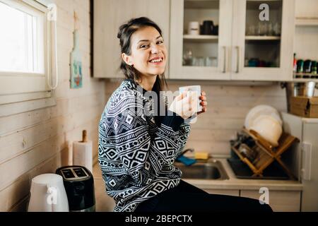 Woman in small kitchen drinking morning coffee.Happiness.Tiny house.First property.Small apartment interior design.Minimalism.Moving in.Living alone.C Stock Photo
