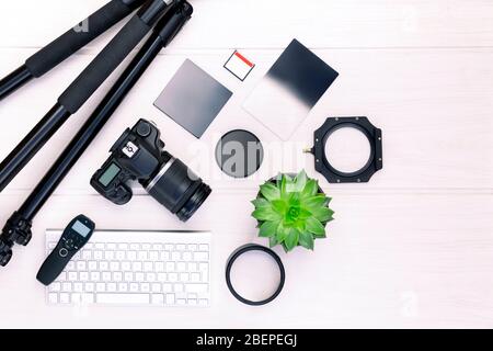 Top view of photographer workplace with dslr camera, lens and camera accessories on white wooden table with copy space for text. Photography concept. Stock Photo