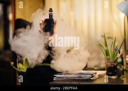 Exhaling the vapor with electronic cigarette.Puffing clouds of smoke.Vape  flavor liquid chemicals.Use of e-cigarettes in the home.Smoking and vaping  n Stock Photo
