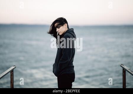 Stressed sad woman in bad mood overthinking problems,looking at the sea/ocean.Person being alone.Social distancing loneliness.Emotional challenge and Stock Photo