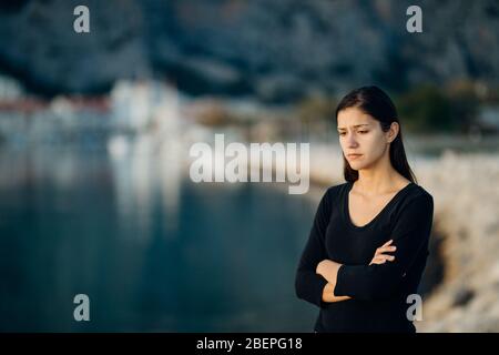 Stressed sad woman in bad mood overthinking problems,looking at the sea/ocean.Person being alone.Social distancing loneliness.Emotional challenge and Stock Photo