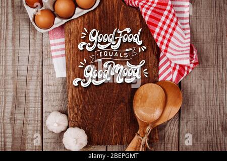Wooden cutting board on a wooden background with garlic, ladles and eggs with the text Stock Photo