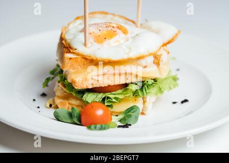 Grilled toast sandwich with cheese and sunny side up fried egg.Two croque-monsieur sandwiches.Double panini with ham and cheese.Breakfast inspiration. Stock Photo