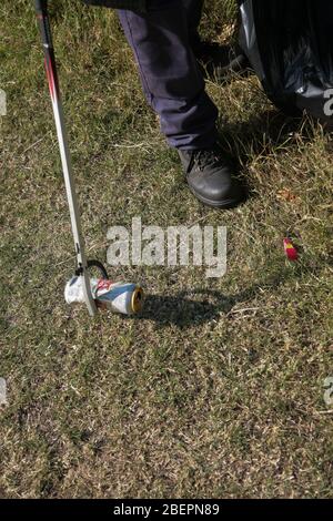 Discarded empty drink cans being collected by a litter picker. Stock Photo