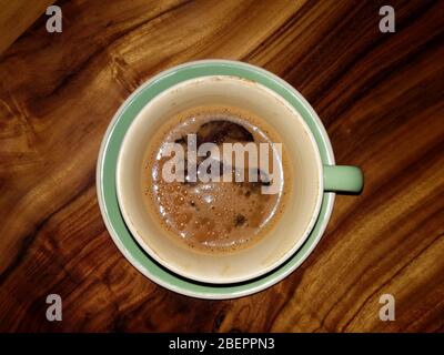 Light green cup of espresso coffee on the saucer on wooden table. Stock Photo