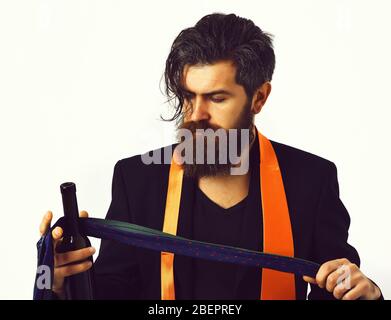Bearded man, long beard. Brutal caucasian hipster with moustache in black suit with colorful ties on shoulders holding bottle isolated on white studio background Stock Photo