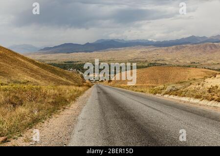 The highway from Bishkek to Osh in front of the Toktogul reservoir in Kyrgyzstan. asphalt road Stock Photo