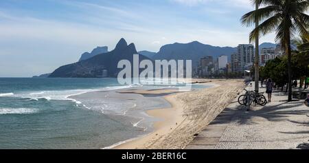 Almost empty Ipanema beach and boulevard with the Two Brothers mountain in the background during the COVID-19 outbreak in Rio de Janeiro Stock Photo