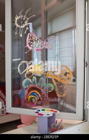 Childrens drawing on the glass window with paints. The concept of home self-isolation. Young artist learns to draw Stock Photo