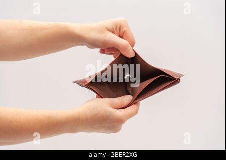 Hands holding and showing open brown leather wallet with no money. Concept: World economic crisis. Isolated on white background. Close-up. Copy space. Stock Photo