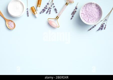 Frame of natural organic SPA lavender cosmetics on blue background. Beauty products for body care and face skin treatment. Flat lay, top view Stock Photo