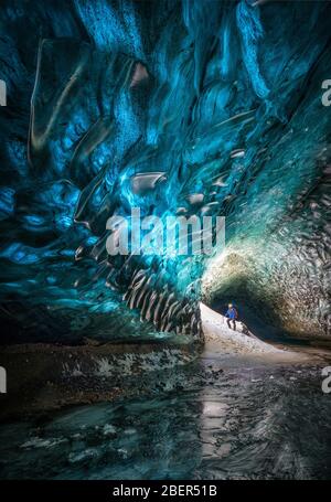 Ice cave showing a guy looking at the ice running through the holes Stock Photo