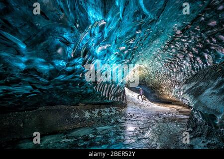 Ice cave showing a guy looking at the ice running through the holes. Stock Photo