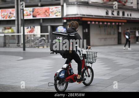 OSAKA, JAPAN - APRIL 15: An Uber Eats delivery man rides a bicycle