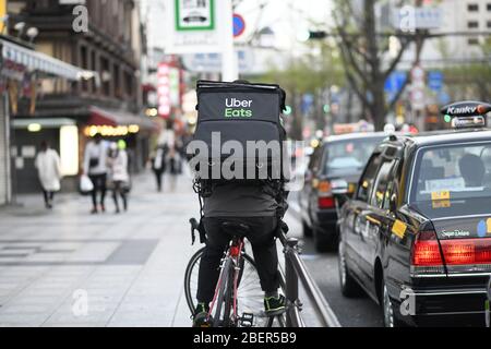 OSAKA, JAPAN - APRIL 15: An Uber Eats delivery man rides a bicycle 