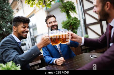 Cheerful old friends having fun and drinking beer at bar counter in pub. Stock Photo