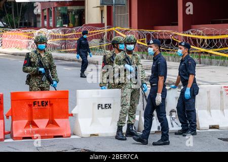 Kuala Lumpur, Malaysia. 15th Apr, 2020. Soldiers and police are on duty in front of a building under the enhanced movement control order (EMCO) in Kuala Lumpur, Malaysia, April 15, 2020. The number of COVID-19 cases in Malaysia totaled at 5,072 after 85 new cases were recorded, the Health Ministry said on Wednesday. The newly confirmed cases of 85 is the first time the number dropped to a double-digit for over a month. Credit: Zhu Wei/Xinhua/Alamy Live News Stock Photo
