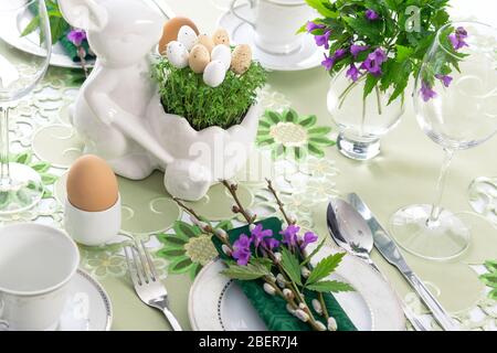 Elegant Easter holiday table settings decoration with fresh early spring violet flowers, cress leaves and eggs. Stock Photo