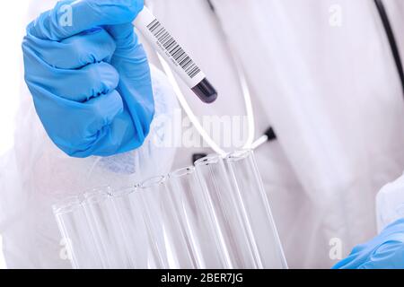Doctor in protective workwear testing blood sample tube in the medical laboratory in close-up Stock Photo