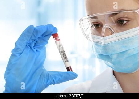 Young woman in protective workwear testing blood sample tube in the medical laboratory Stock Photo