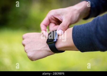 Man in nature using smartwatch app. Close-up hands Stock Photo