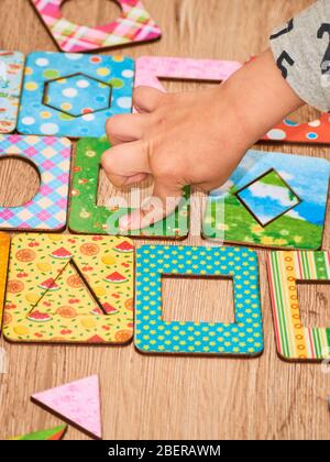 Kid's hands with Montesori pazzls close-up. Montesori wooden game for the development of children. Child development retardation. Stock Photo