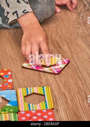 Kid's hands with Montesori pazzls close-up. Montesori wooden game for the development of children. Child development retardation. Stock Photo