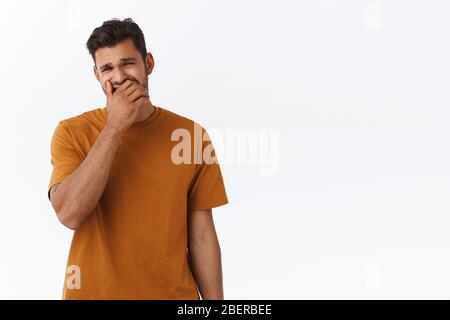 Bored, indifferent handsome bearded guy with stylish hipster haircut feeling unamused and uninterested as attend boring party, yawning sleepy and Stock Photo