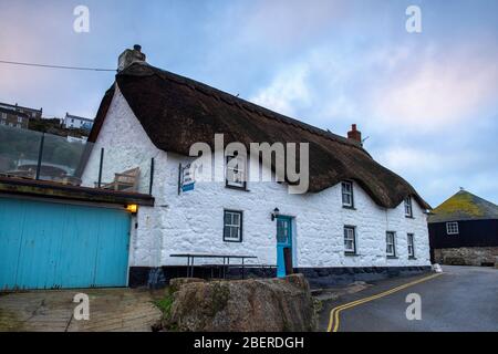 Thatched Cottage at sunrise, by the harbour in Sennen Cove, Cornwall England UK Stock Photo