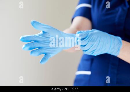Nurse putting on vinyl gloves Stock Photo