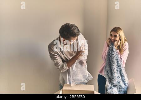 Handsome man and happy girl unpacking tableware after moving into new apartment. Stock Photo