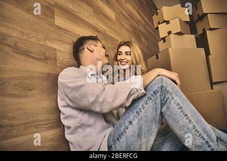 Young beautiful lovely couple sitting on the floor and relaxing after moving to new apartment. Stock Photo