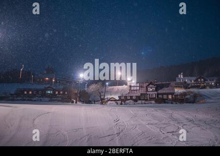 VELKA UPA, CZECH REPUBLIC, MARCH 2020 - Ski village at night with slope lights, cross-country ski run, buildings Stock Photo