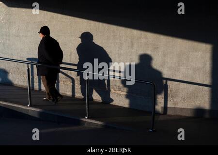 Istanbul, Turkey - March 12, 2011 : Walking senior man and shadows of people on the wall at Istanbul. Stock Photo