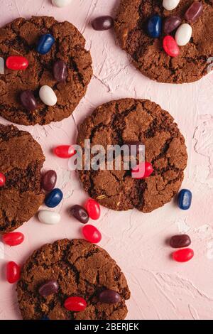 Homemade oat chocolate cookies with cereal with juicy jelly beans on textured pink background, top view Stock Photo