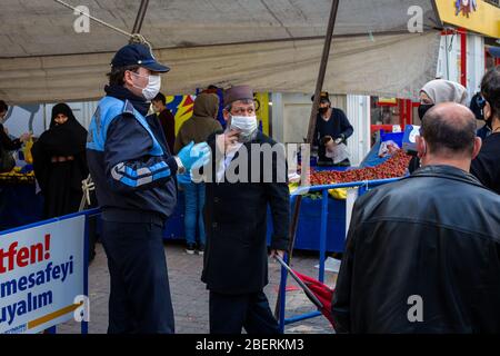 April 14, 2020: Zeytinburnu municipal officers give medical mask to prevent people from coronavirus at street market on April 14, 2020, in Zeytinburnu district, Istanbul, Turkey. On March 27, 2020, the Ministry of the Interior issued an additional circular on market places as part of struggle the coronavirus outbreak. Accordingly, the sale of non-essential supplies other than basic food and cleaning agents will not be allowed. Necessary measures will be taken by the municipalities regarding hygiene and disinfection in the market places. (Credit Image: © Tolga Ildun/ZUMA Wire) Stock Photo