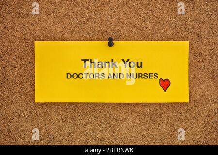 Thank you doctors and nurses written on a yellow piece of paper that is on a bulletin board. Coronavirus concept. Close up. Stock Photo